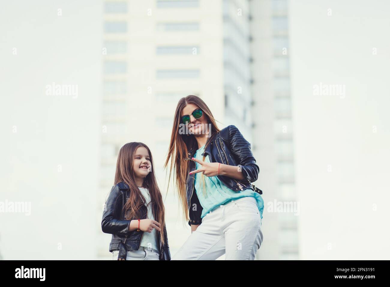 Look tendance pour toute la famille. Femme avec enfant fille en famille  vêtements à la mode ayant l'amusement à l'extérieur. Mode jeune mère et  enfant fille portant un verre de soleil Photo