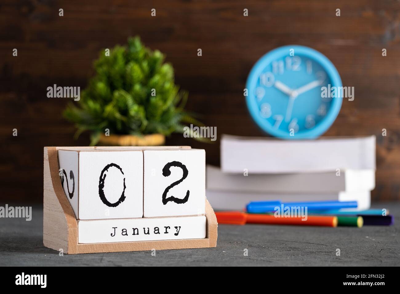 02 janvier. Janvier 02 calendrier cube en bois avec des objets flous sur fond. Banque D'Images