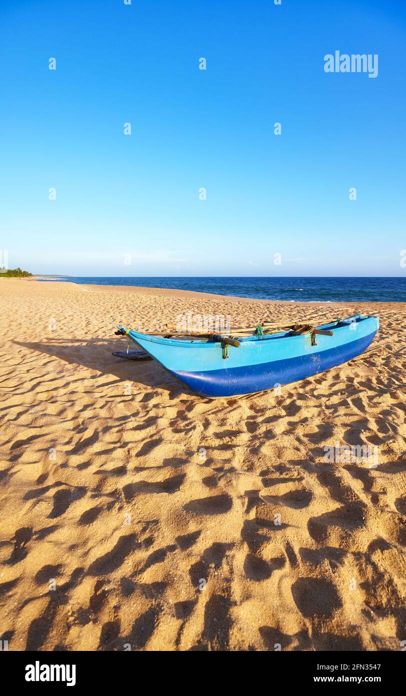 Petit bateau de pêche sur une plage vide au coucher du soleil, Sri Lanka. Banque D'Images