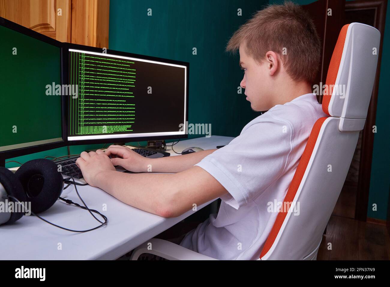 Un jeune programmeur imprime le code de programme sur l'écran de l'ordinateur. Le concept de sécurité informatique, de développement technologique et de jeune prof Banque D'Images