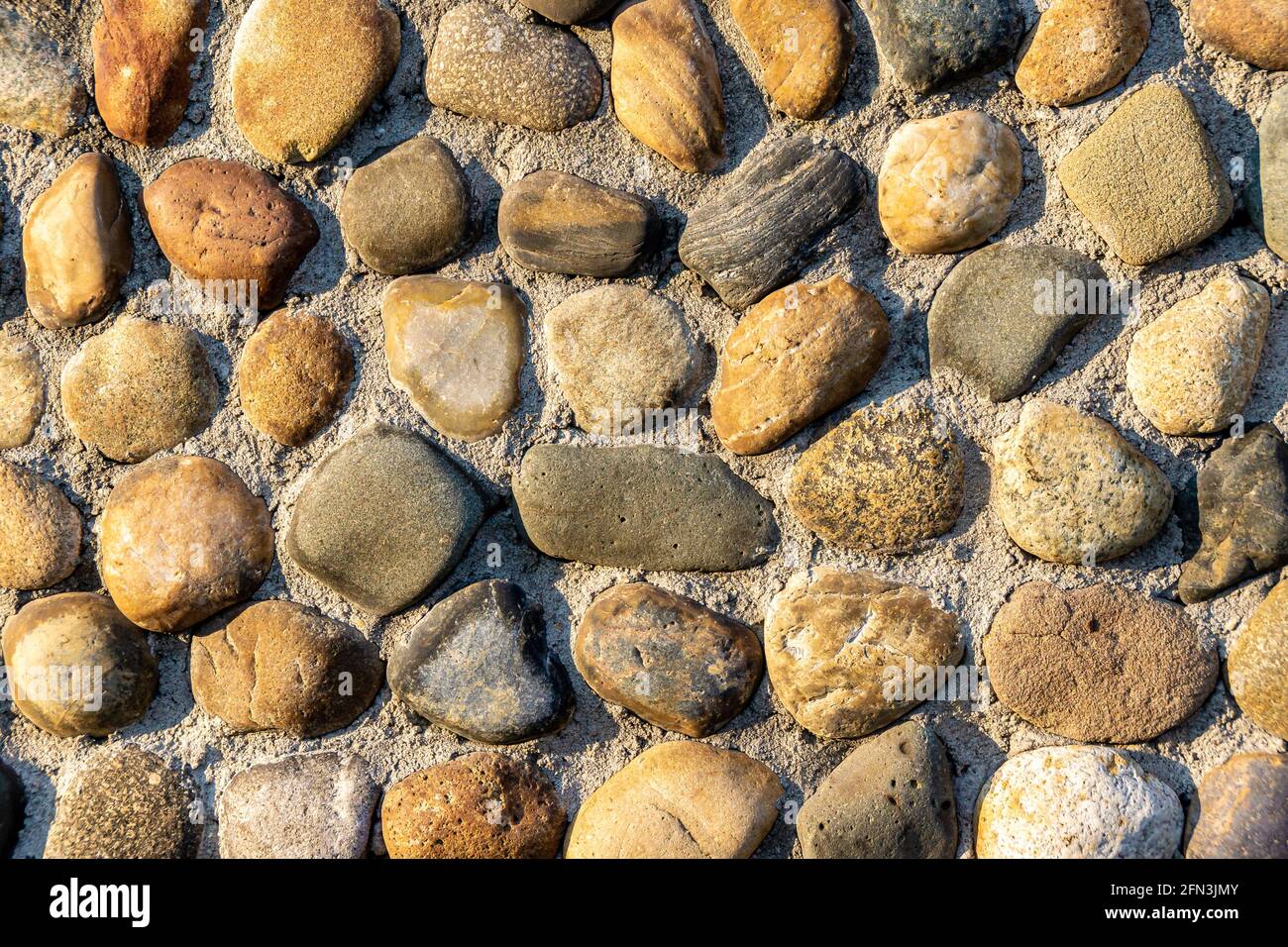 les pierres de cailloux se trouvent en rangées partiellement enfoncées dans la surface principale du mur, de la route ou du plancher Banque D'Images