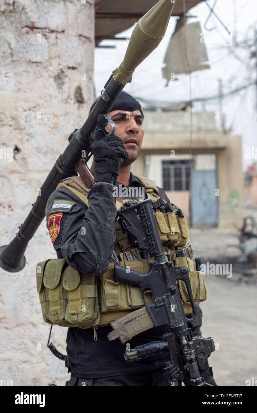 Un membre des forces spéciales iraquiennes garde un point de distribution alimentaire dans le district d'Al Bakir, à Mossoul est, en Iraq. Banque D'Images