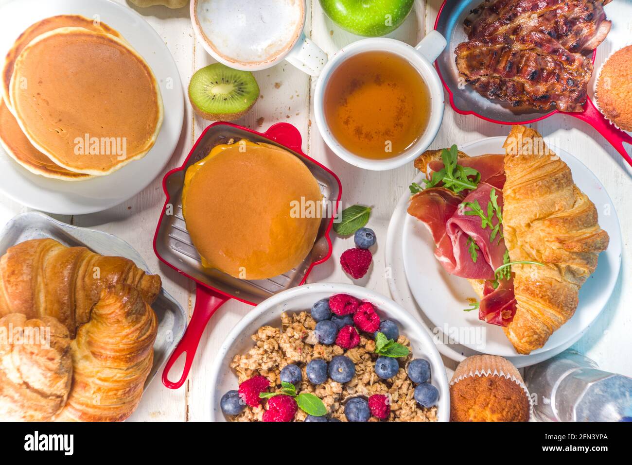 Divers plats traditionnels pour le petit déjeuner - œufs frits avec bacon, muesli, avoine, gaufres, crêpes, hamburger, croissants, fruits, café, thé et orange j Banque D'Images