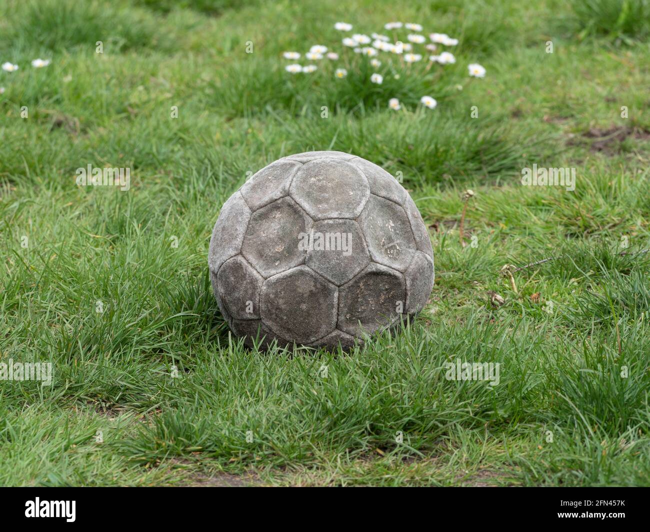 Le vieux football en cuir patiné est plat et se trouve dans le herbe Banque D'Images