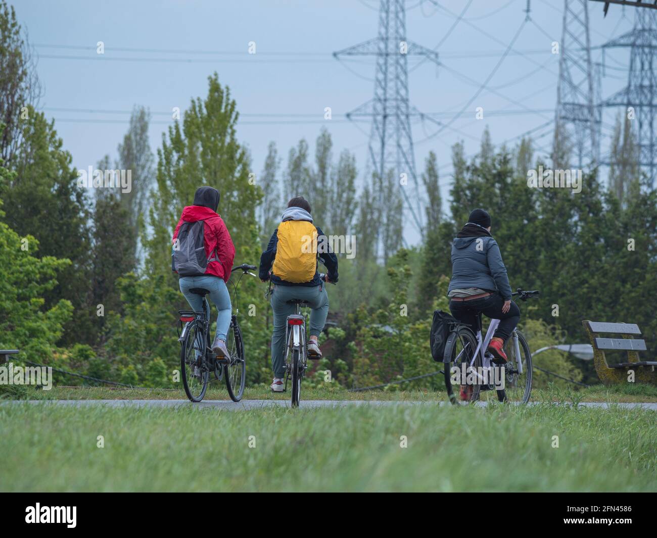 Trois amis sur des vélos en équipement de pluie sur un pluvieux jour Banque D'Images