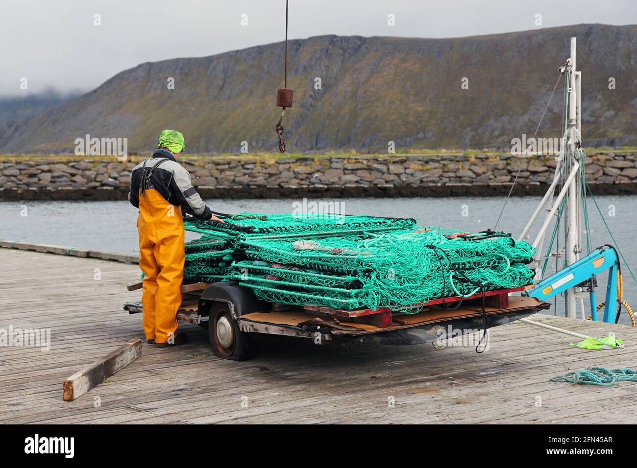 Un pêcheur norvégien prépare les outils de travail. Travailleur pliant une grande cage de crevettes. Chalutage des crevettes et des crabes dans les fjords norvégiens. Banque D'Images