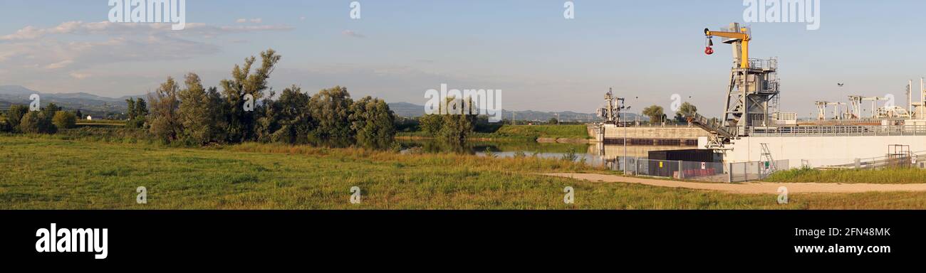 Énorme barrage sur une rivière à la campagne. Photo panoramique de grand barrage avec grue jaune sur le dessus. Paysage de campagne en été. Protection du territoire. Banque D'Images