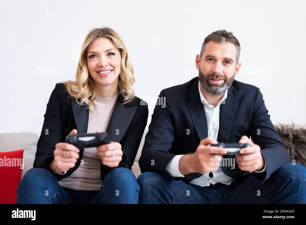 Couple élégant jouant à des jeux vidéo. Les gens d'affaires souriants s'amusent à la console pendant une pause. Développeurs de logiciels qui tiennent des joysticks. Banque D'Images