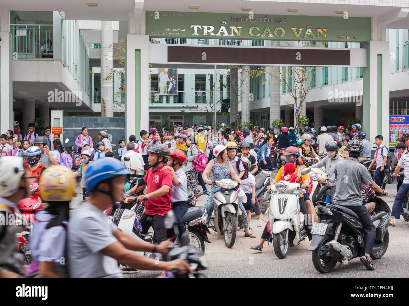 Zone congestionnée comme beaucoup de parents arrivent aux portes de l'école sur les motos et les scooters sur l'après-midi école de course, Da Nang, Vietnam Banque D'Images