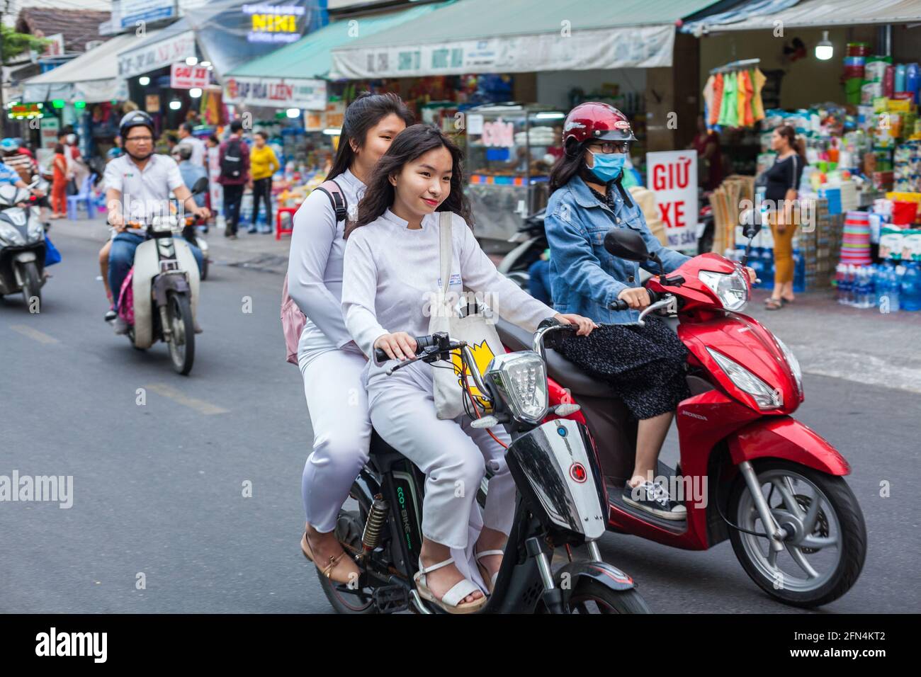 Jolies écolières vietnamiennes portant des robes blanches traditionnelles ao dai conduire scooter sans casque de crash, Da Nang, Vietnam Banque D'Images