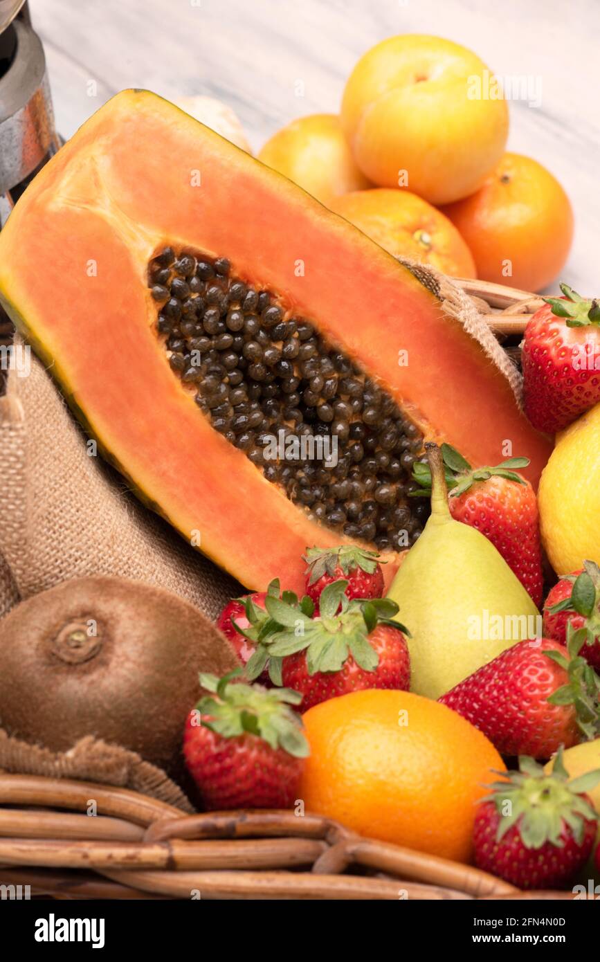 Panier de fruits tropicaux, oranges, poires kiwi papaye avec un batteur sur une table en bois. Verticale Banque D'Images