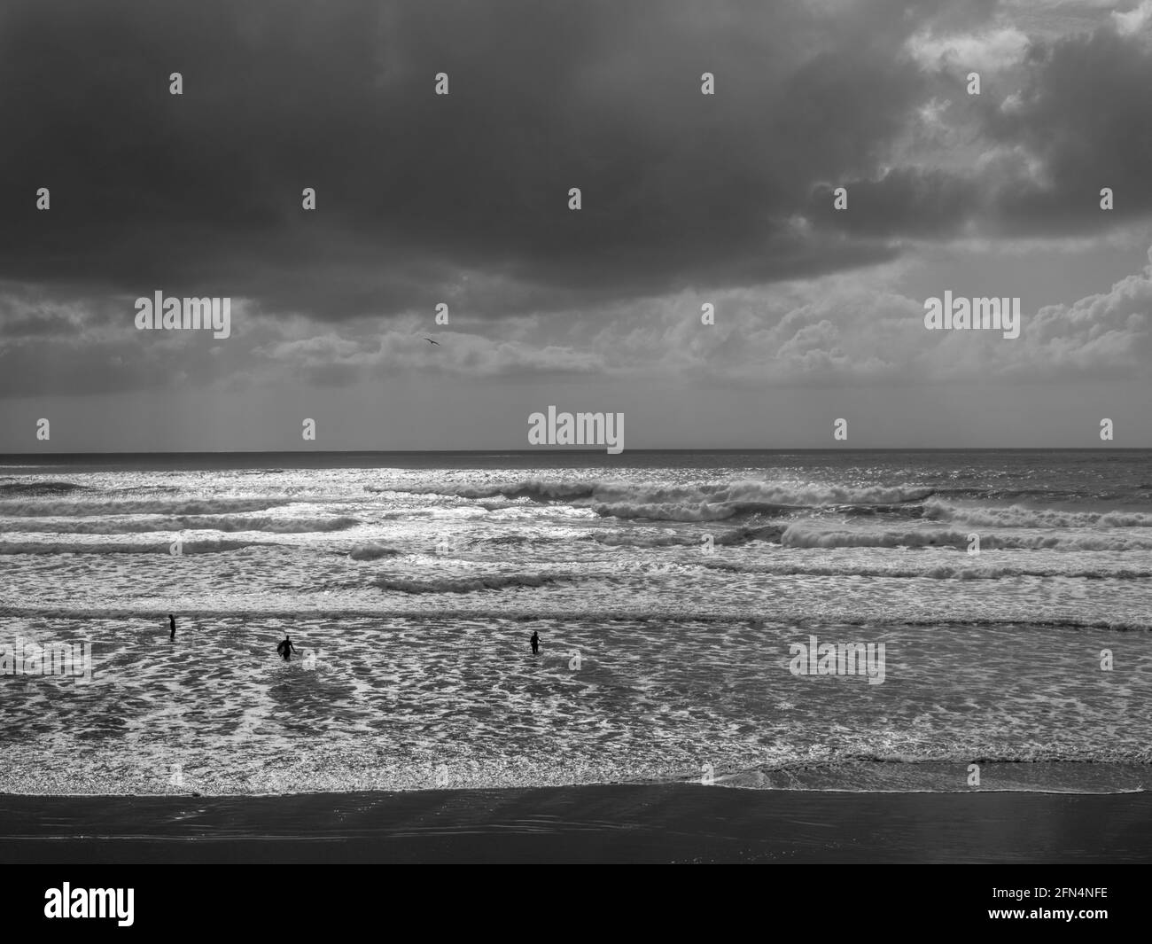 Paysage marin par mauvais temps au large de la côte nord du Devon avec des surfeurs et nageurs non identifiables. Banque D'Images