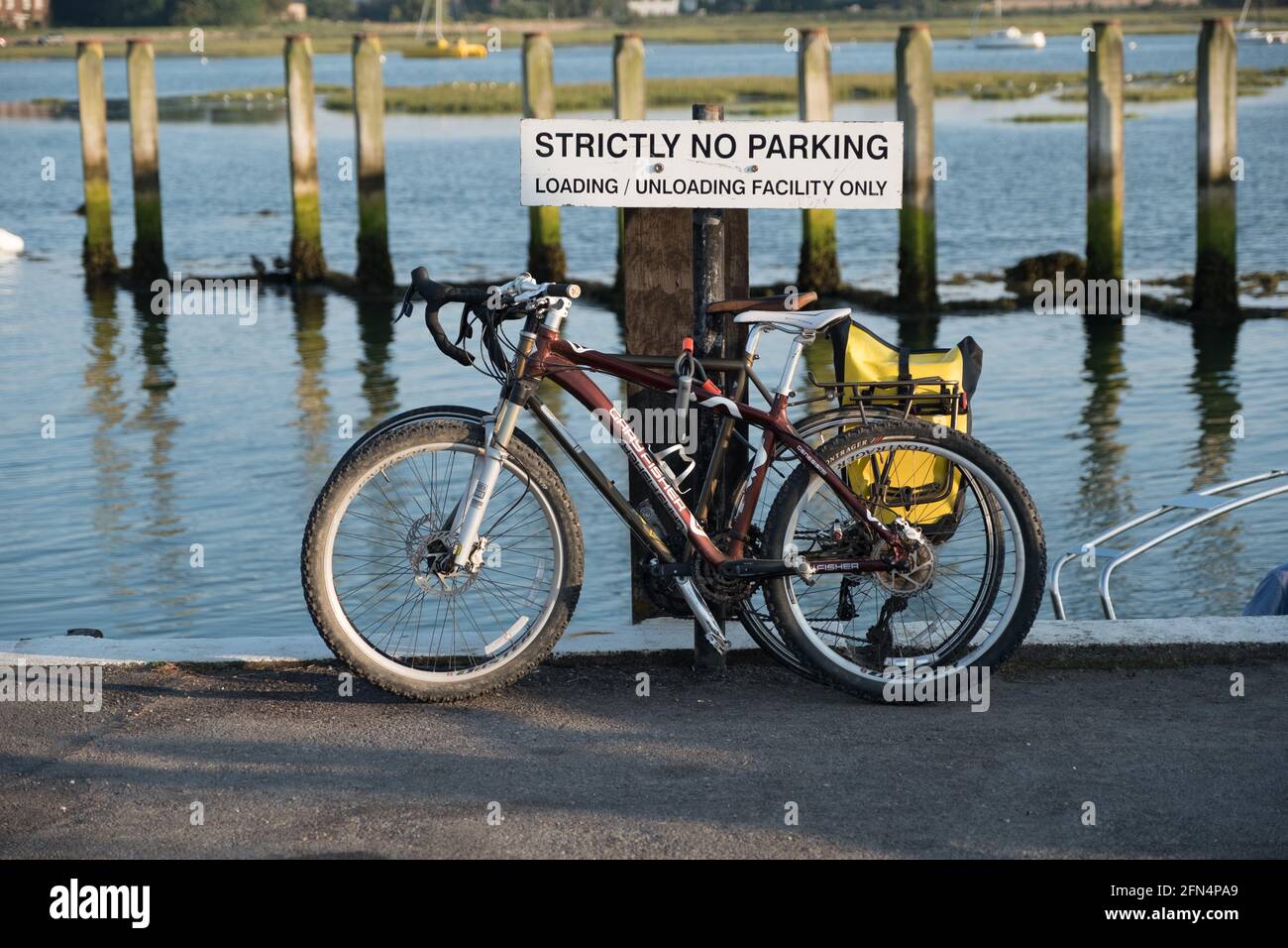 Deux vélos à pédales garés au bord de la mer contre un avis disant strictement pas de stationnement. Banque D'Images