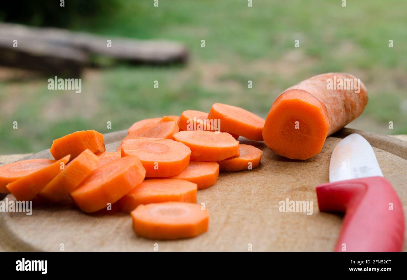 carottes déjà coupées, avec son couteau sur le côté, sur le bois dans le jardin vert source de vitamine d et une alimentation saine Banque D'Images