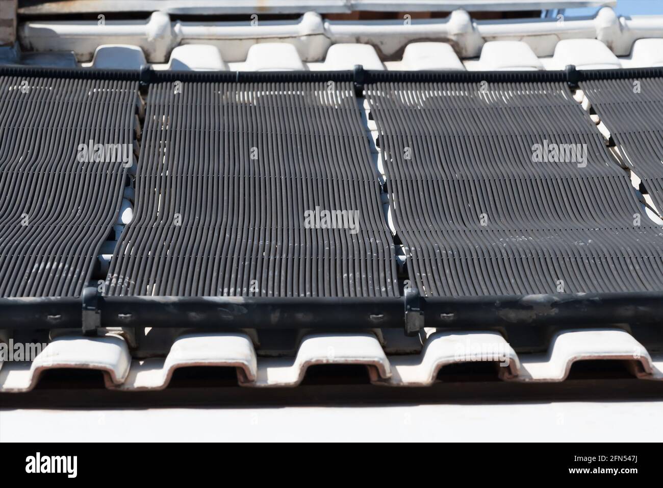 Système de tubes solaires de chauffage de l'eau sur le toit d'une maison. Chauffage solaire de piscine avec tubes noirs, solution écologique. Banque D'Images