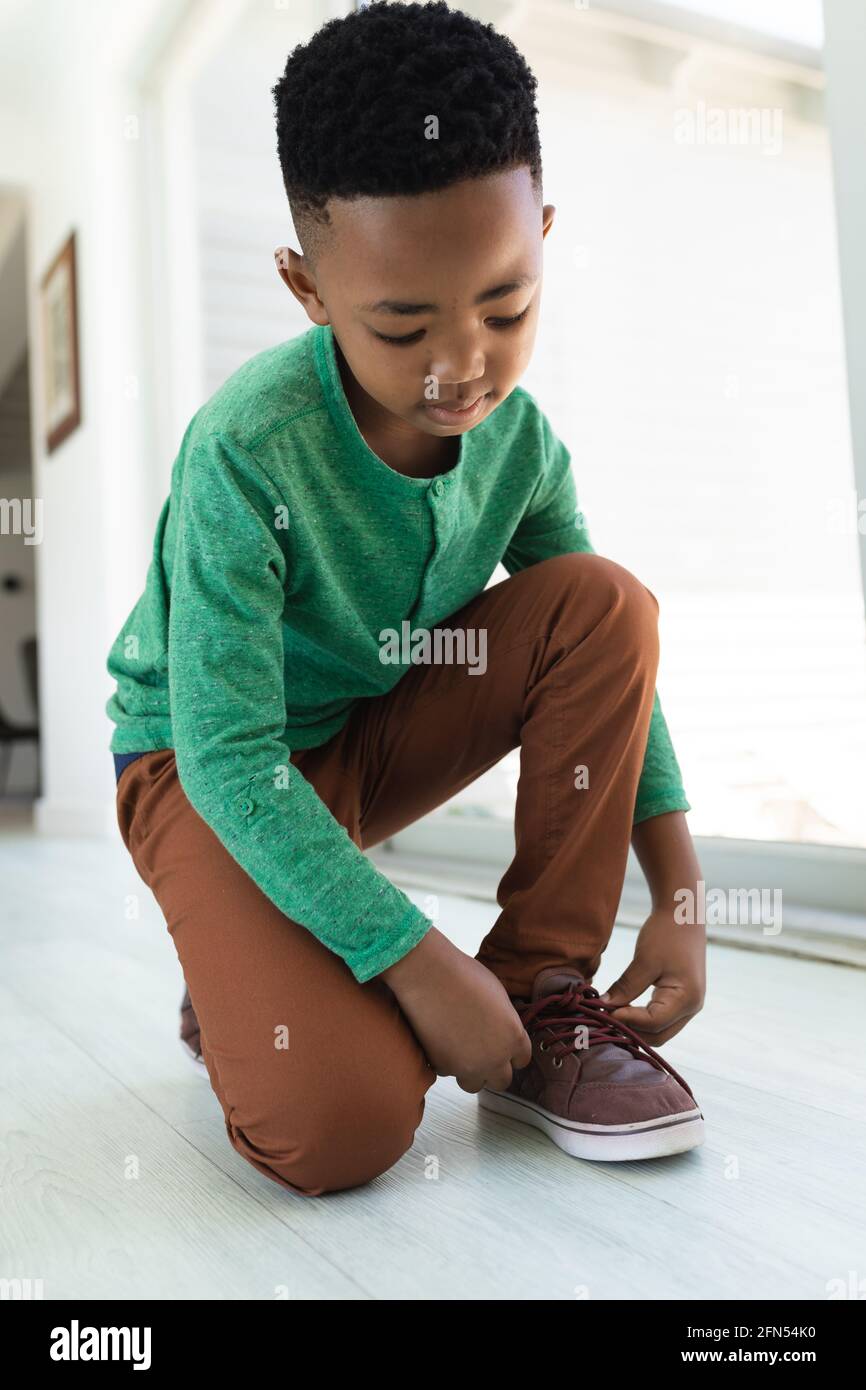 Un garçon afro-américain assis sur le sol, nouant des lacets de chaussures  Photo Stock - Alamy