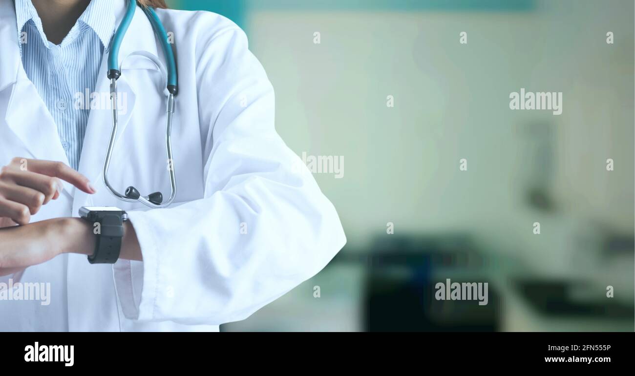 Composition de la section médiane de la femme médecin en blouse de laboratoire utilisant montre intelligente hors de la portée de l'hôpital Banque D'Images