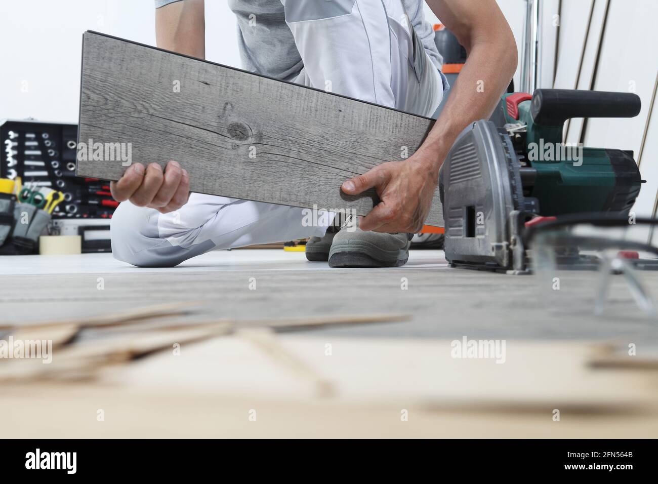 Les mains du travailleur installant un plancher en vinyle laminé en bois. Rénovation de maisons en parquet. Banque D'Images