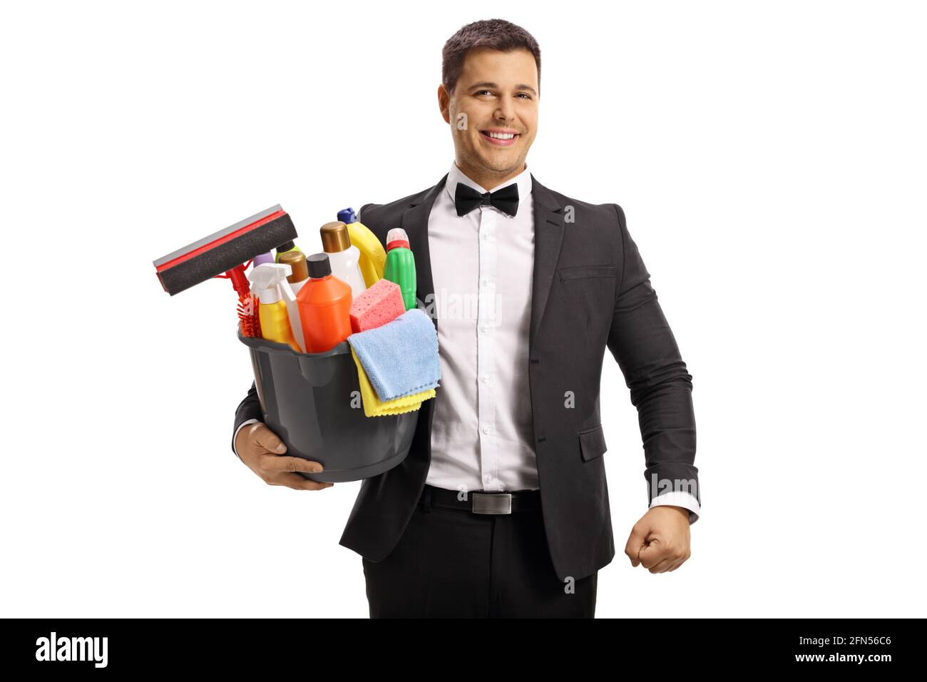 Jeune homme en costume et noeud portant un seau avec fournitures de nettoyage isolé sur fond blanc Banque D'Images