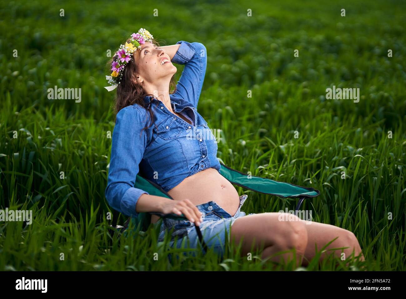 Bonne jeune femme enceinte dans un champ de blé dans le campagne Banque D'Images