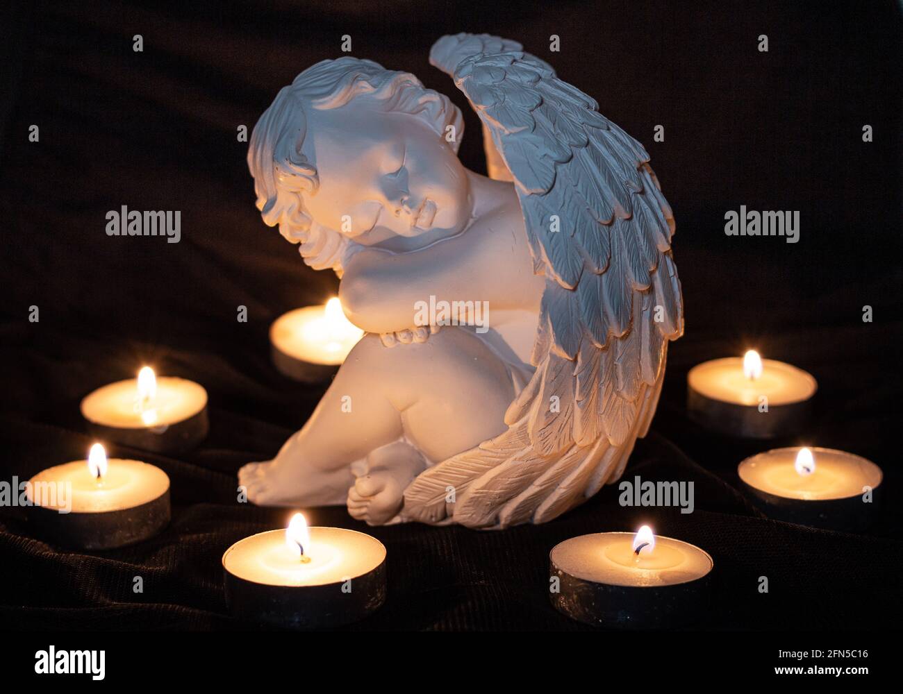 sculpture d'ange entourée de bougies en feu; mémoire de chagrin et de perte  du concept de morts Photo Stock - Alamy