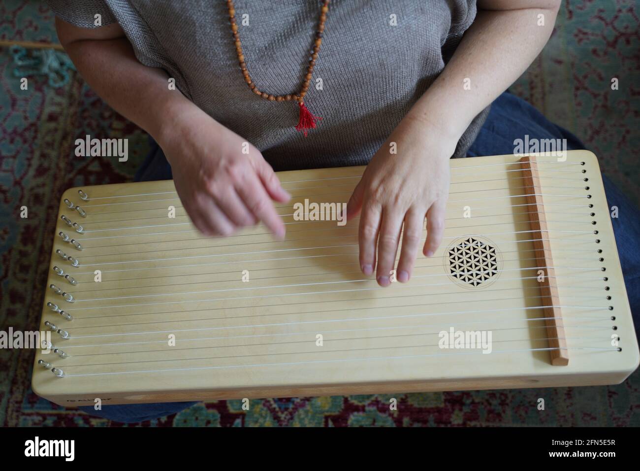 Femme tenant un instrument de guérison sonore monocorde dans une séance de thérapie. Banque D'Images