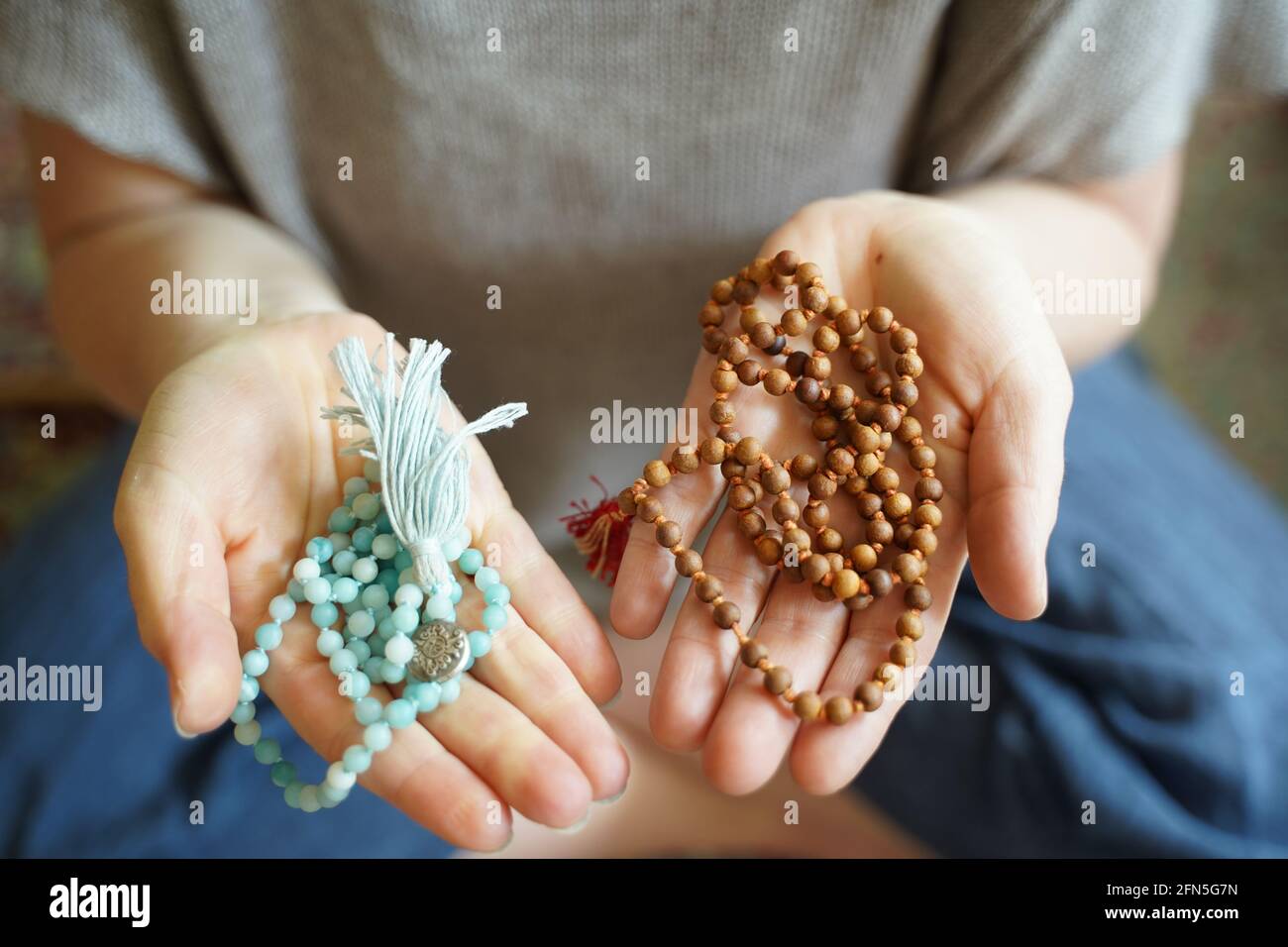 Une femme tenant un collier de perles de prière de yoga mala dans chaque main. Banque D'Images