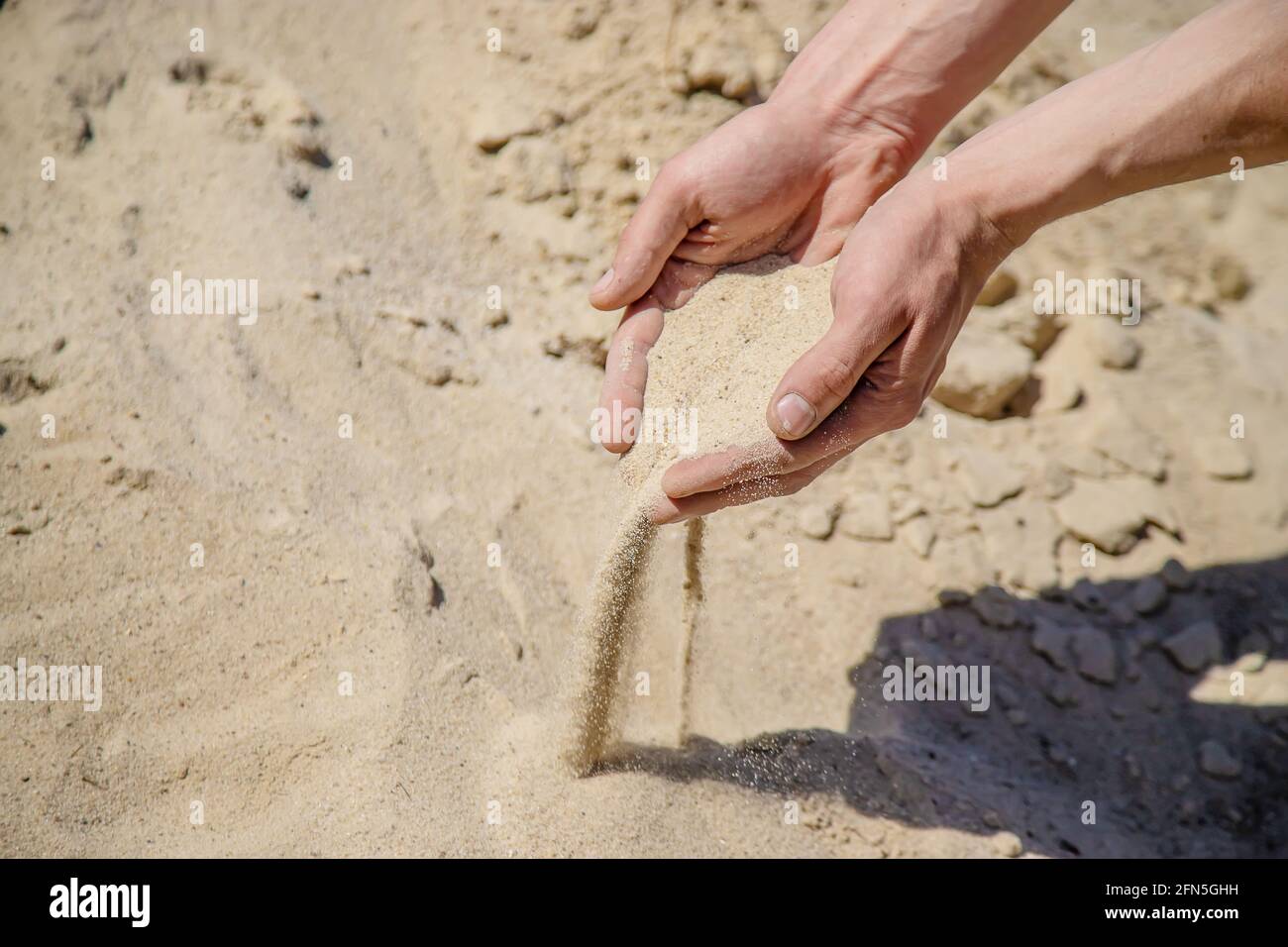 Homme tenant le sable dans ses mains Banque D'Images