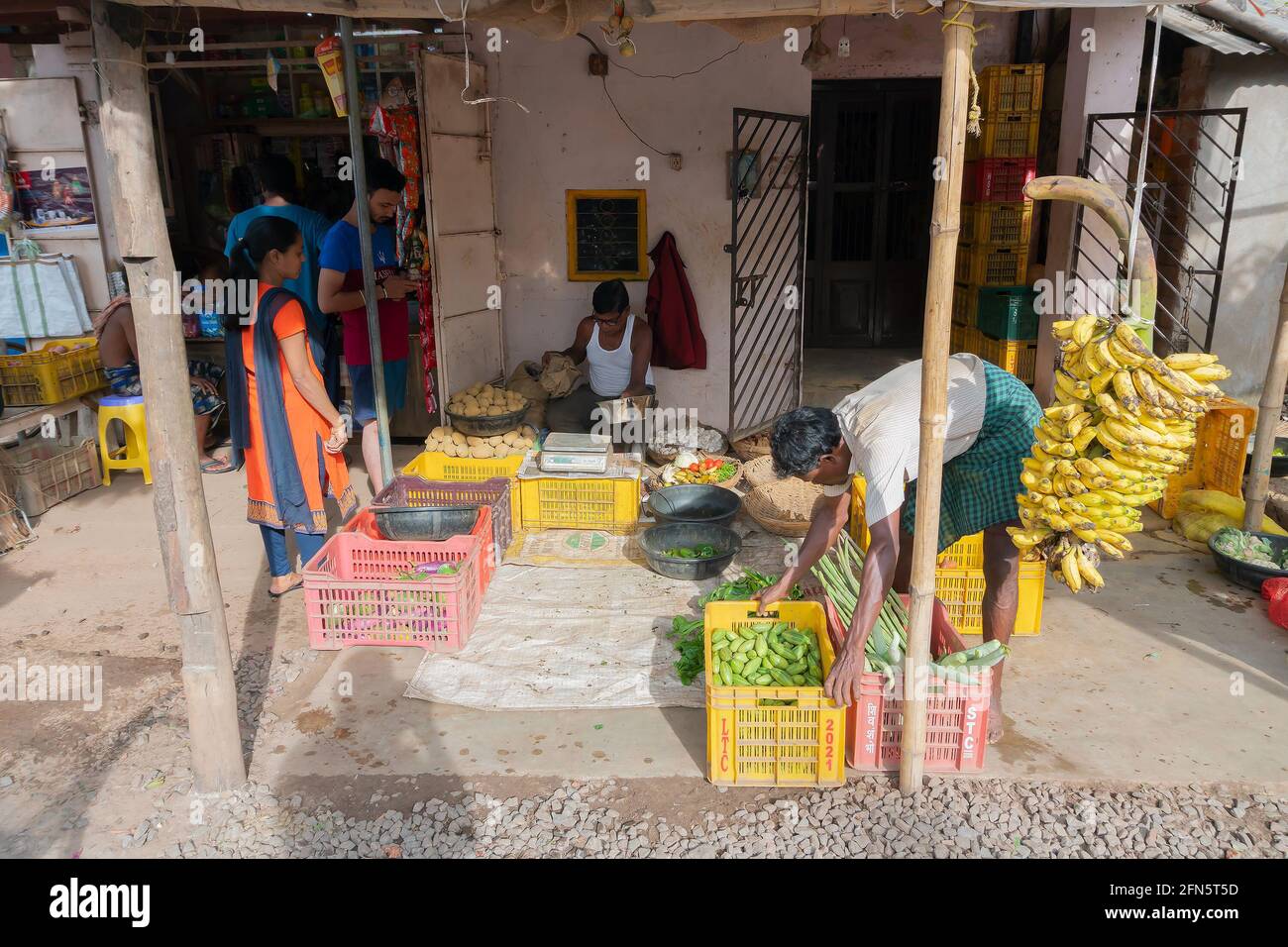 Cuttack, Odisha, Inde - 24 juillet 2019 : les bananes et autres légumes sont vendus en bord de route. Le jeune homme est en train d'arranger les paniers avant de les vendre Banque D'Images