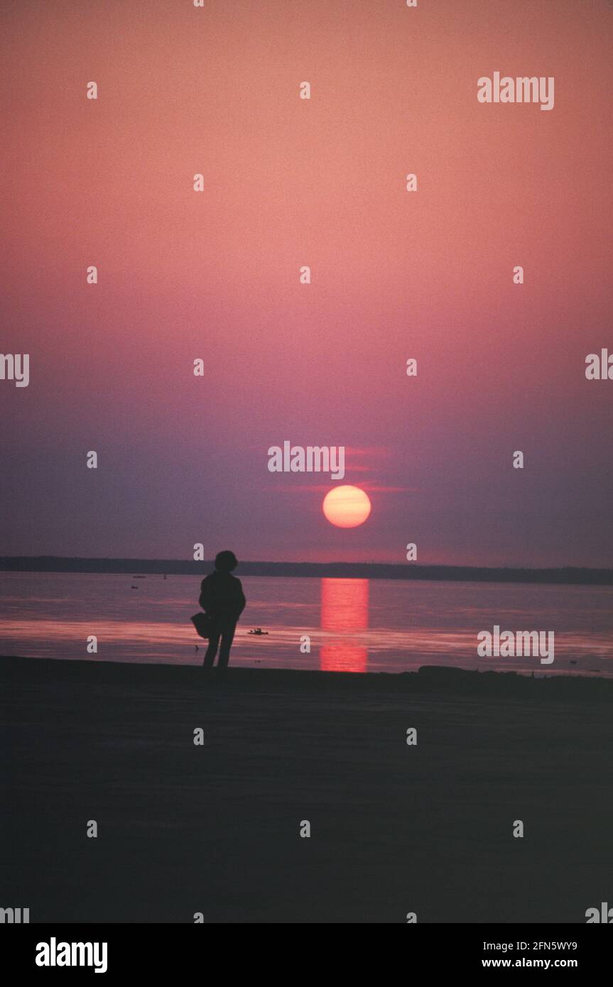 Fédération de Russie. Côte de la mer Baltique. Une seule personne qui regarde le coucher du soleil. Banque D'Images