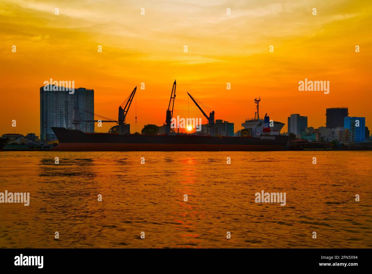 Grues à conteneurs chargement de conteneurs dans le port maritime, terminal logistique d'importation et d'exportation. Coucher de soleil ciel orange horizon Banque D'Images