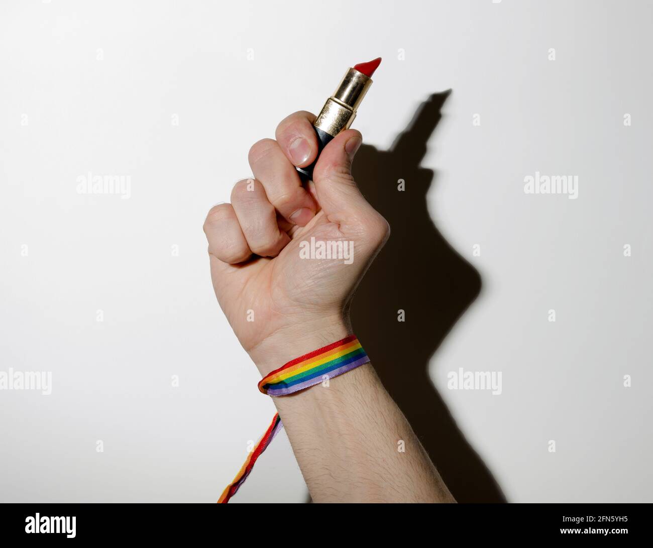 Main gay tenant un rouge à lèvres avec bracelet arc-en-ciel Banque D'Images