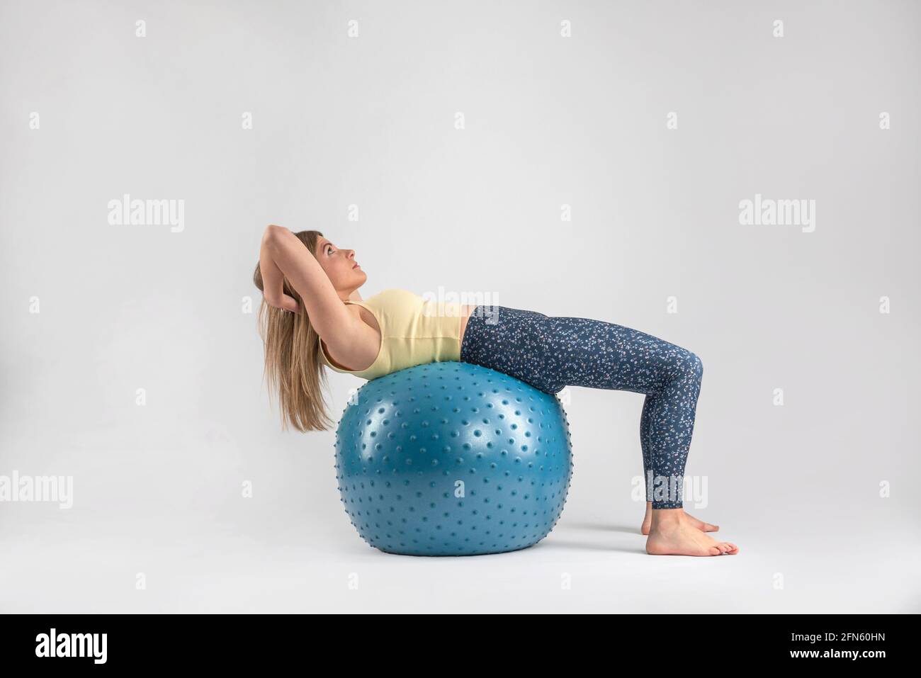 blonde fille exerçant son abs avec pilates balle Banque D'Images