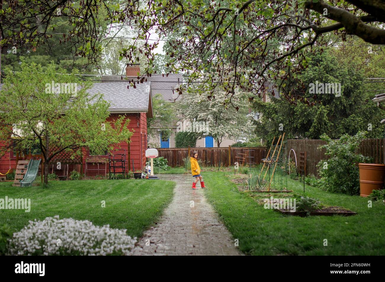 Une petite fille joue dans la pluie battante dans l'arrière-cour jardin Banque D'Images