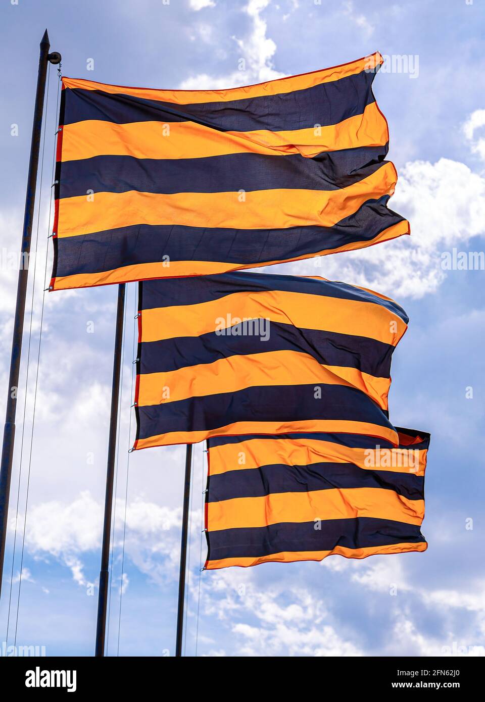 Drapeaux de Saint George agitant dans le vent contre le ciel. Drapeaux de la victoire à rayures orange noires Banque D'Images