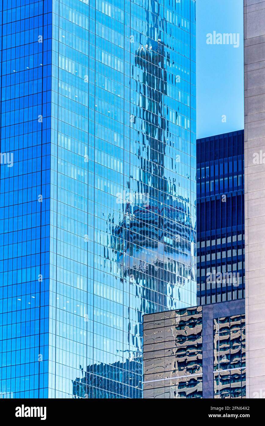 Angle inhabituel de la Tour CN dans le quartier du centre-ville de Toronto, Canada. Le point de repère se reflète dans le verre d'un nouveau gratte-ciel Banque D'Images