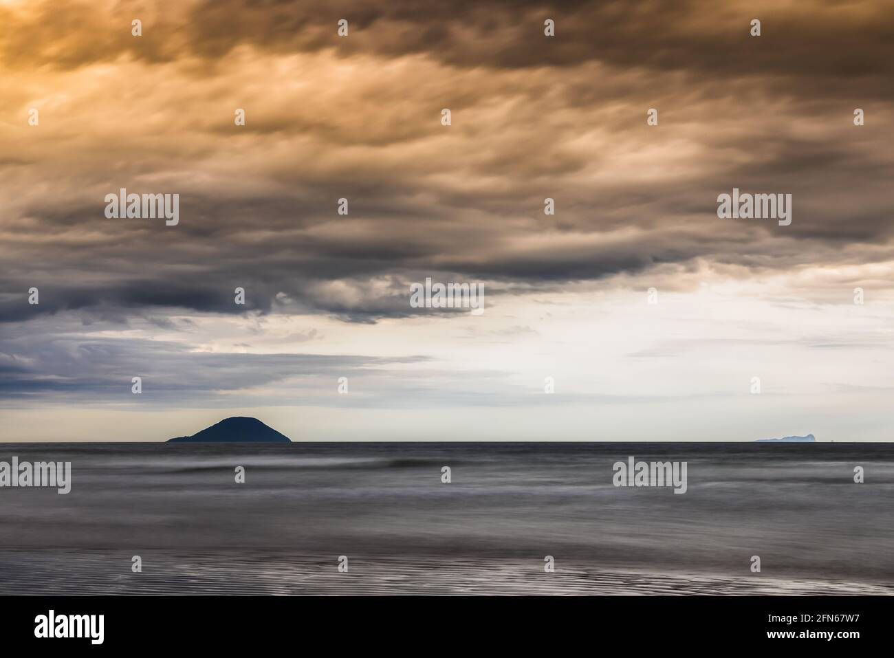 Paysage de plage incluant la mer et une île faite en exposition longue Banque D'Images