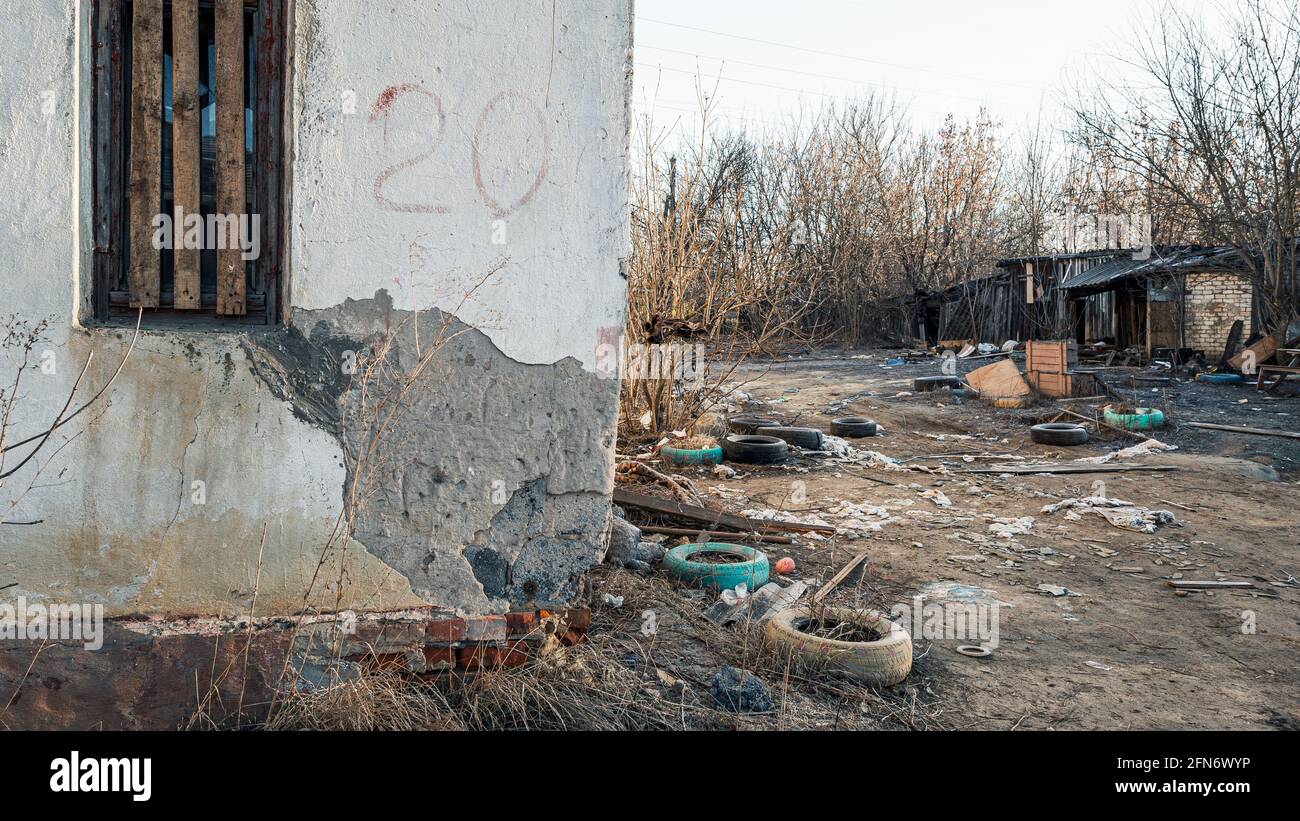 Le mur d'une maison en ruine avec une fenêtre boardée, la destruction et les ordures dans un quartier pauvre Banque D'Images