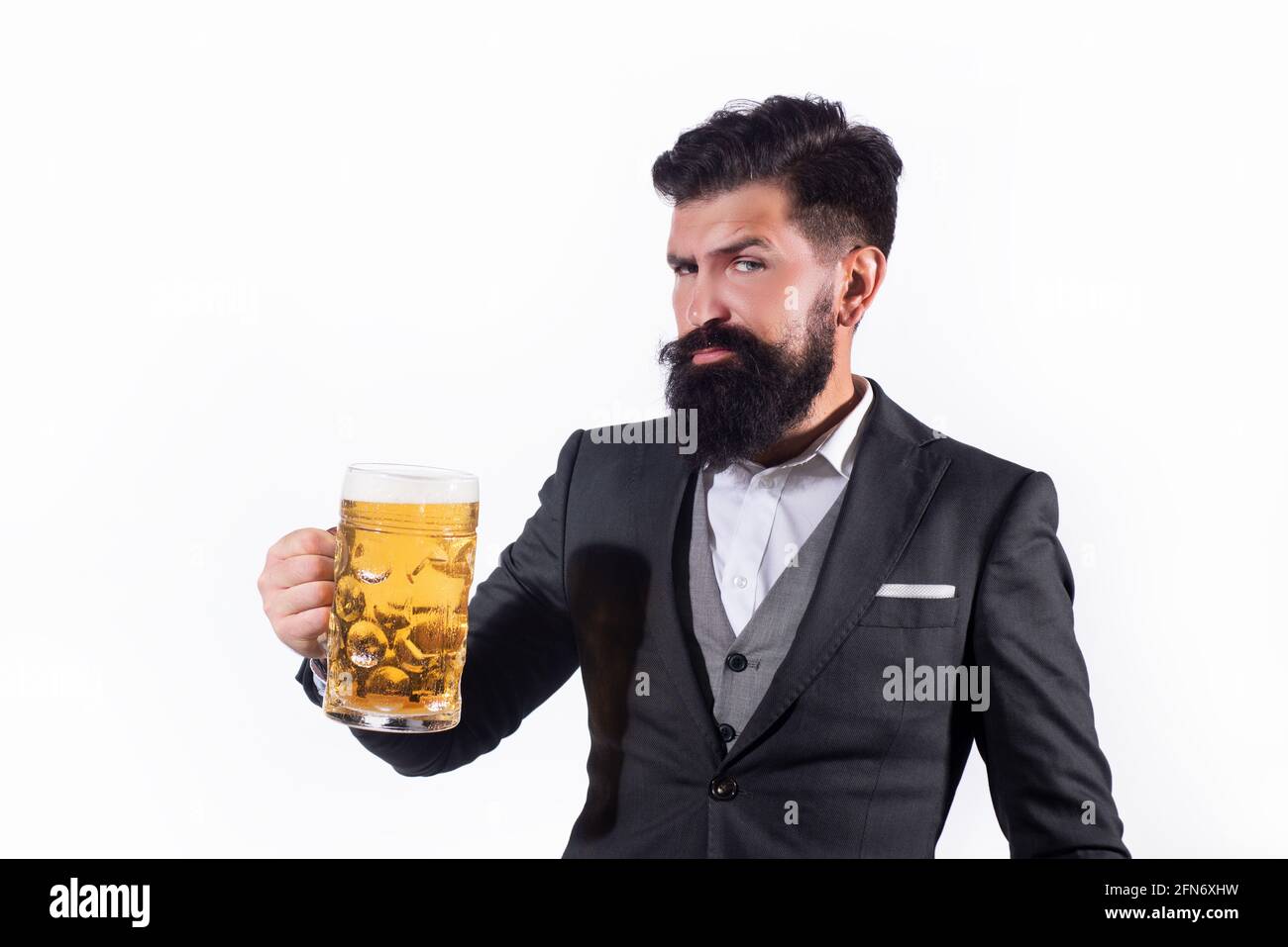 Homme barbu tenant un verre de bière. La taille basse avec barbe et moustache en costume boit de la bière après la journée de travail. Banque D'Images