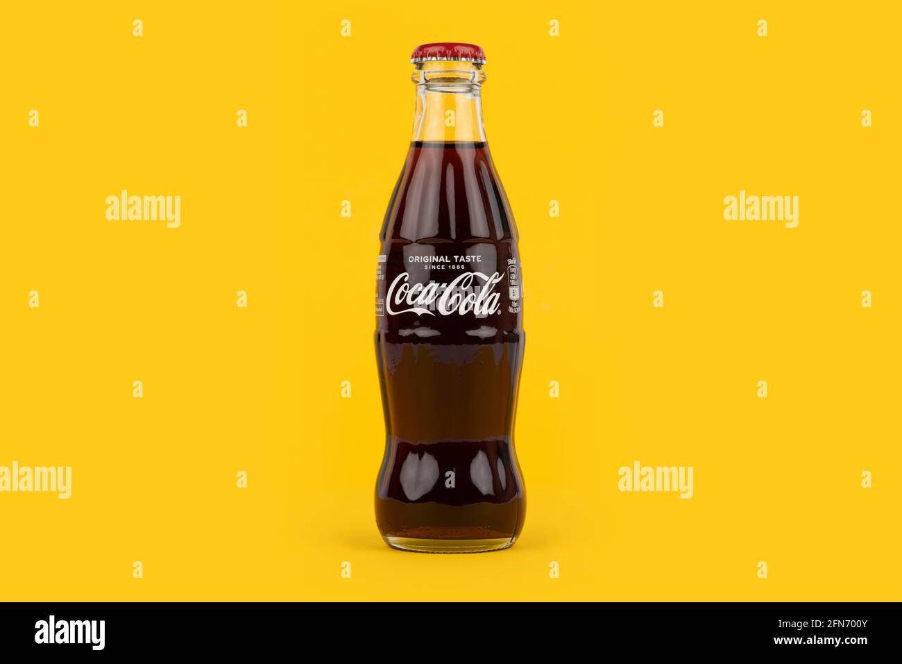 Une bouteille de Coca-Cola de forme traditionnelle sur fond jaune. Banque D'Images