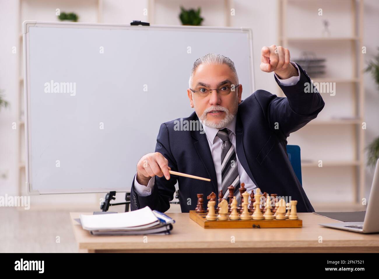 Un vieux employé d'homme d'affaires jouant aux échecs sur le lieu de travail Banque D'Images