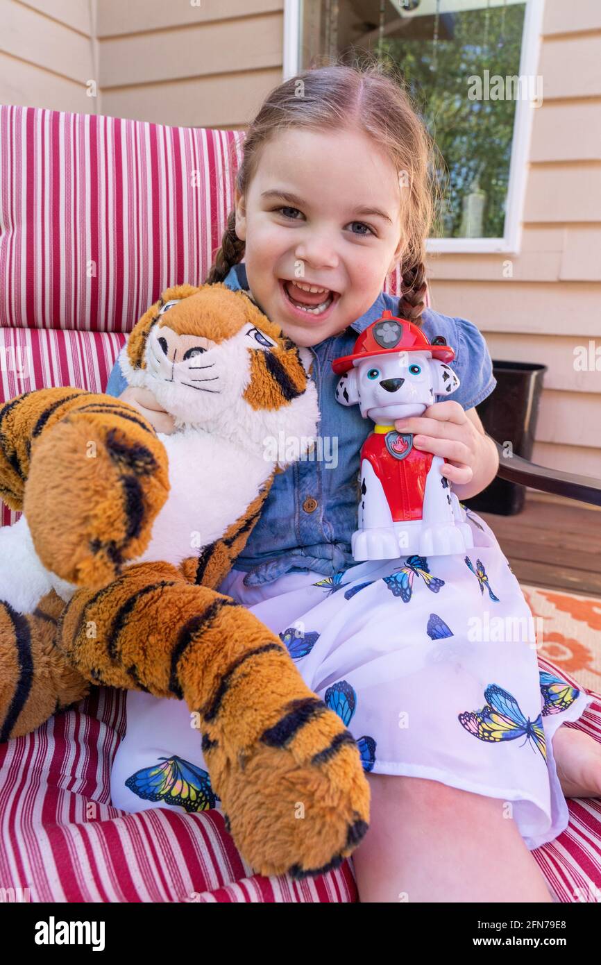 Lynwood, Washington, États-Unis. Jeune fille de quatre ans s'amusant avec son chien et son tigre farcis pompier. (M.) Banque D'Images