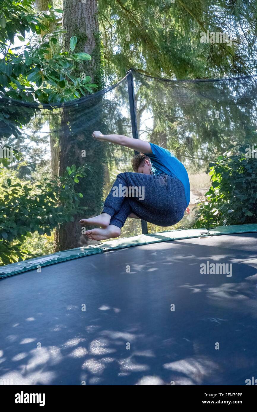Lynwood, Washington, États-Unis. Un garçon de dix-sept ans rebondit en plein air sur un trampoline dans son arrière-cour. (M.) Banque D'Images