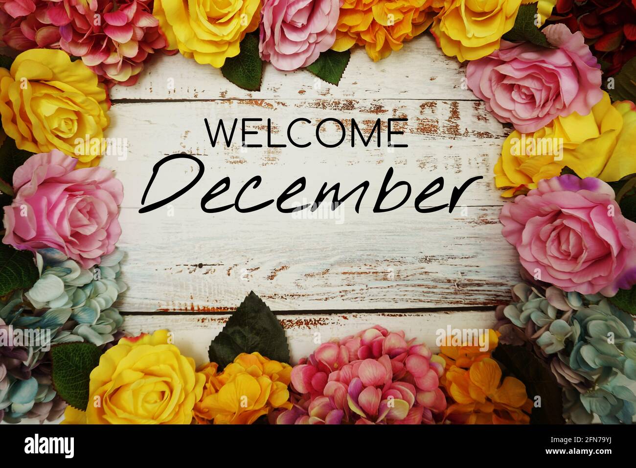 Message texte de bienvenue de décembre avec décoration de bordure de fleurs sur fond en bois Banque D'Images