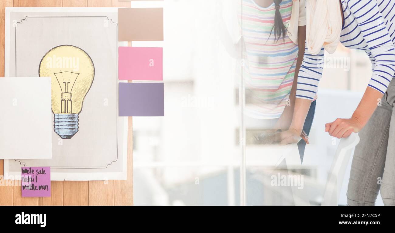 Composition de l'image de l'ampoule sur deux femmes d'affaires diverses Banque D'Images