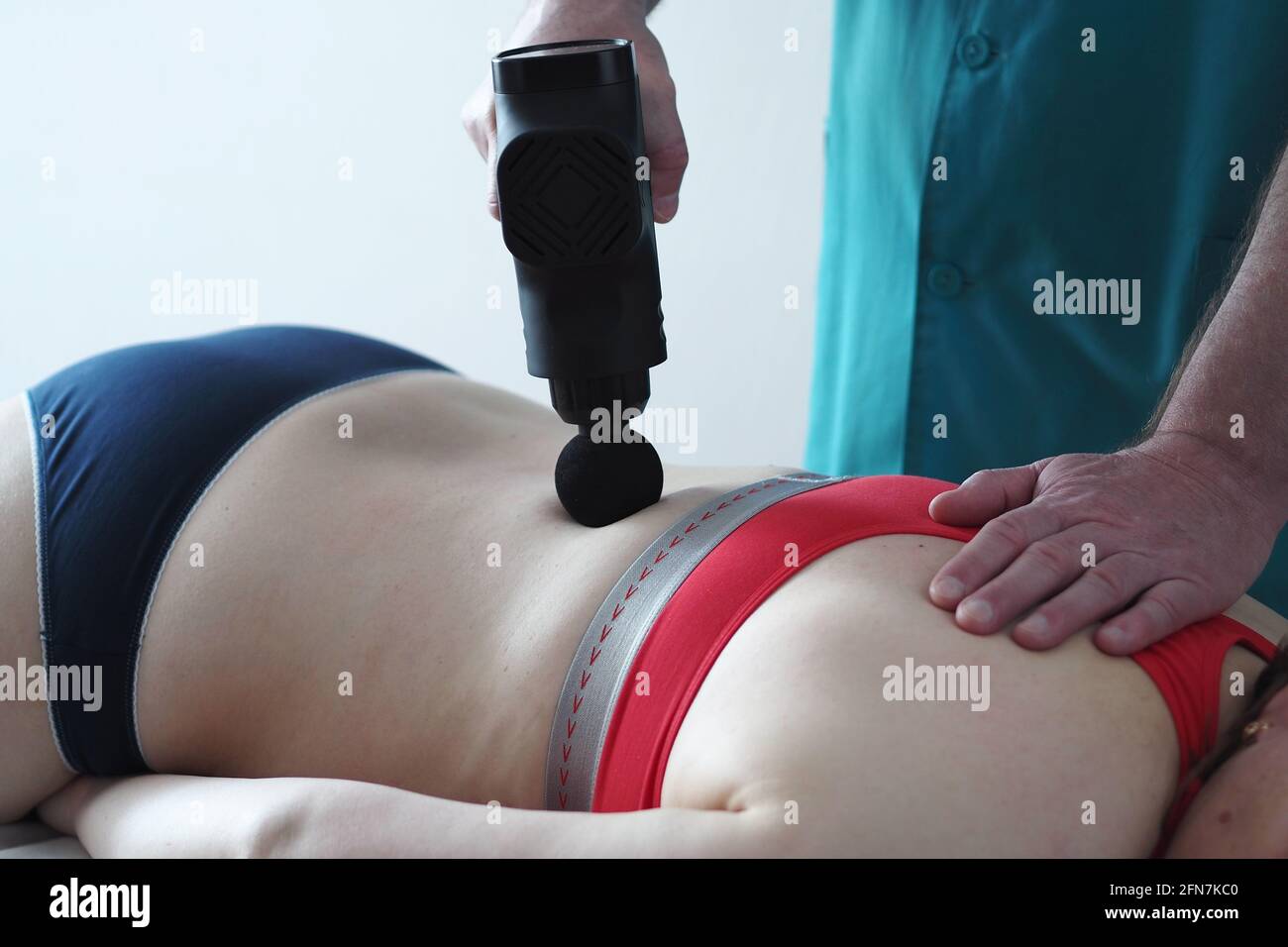 Matériel de massage du dos. Un masseur à percussion. Le patient sur la table de massage. Banque D'Images