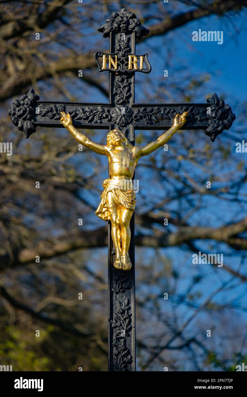 Une croix de fer avec le Christ crucifié sur un arbres de fond et de ciel bleu Banque D'Images