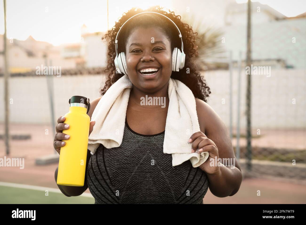 Bonne femme africaine curvy faisant le jogging et la routine d'entraînement pendant ecouter de la musique avec des écouteurs sans fil en extérieur Banque D'Images