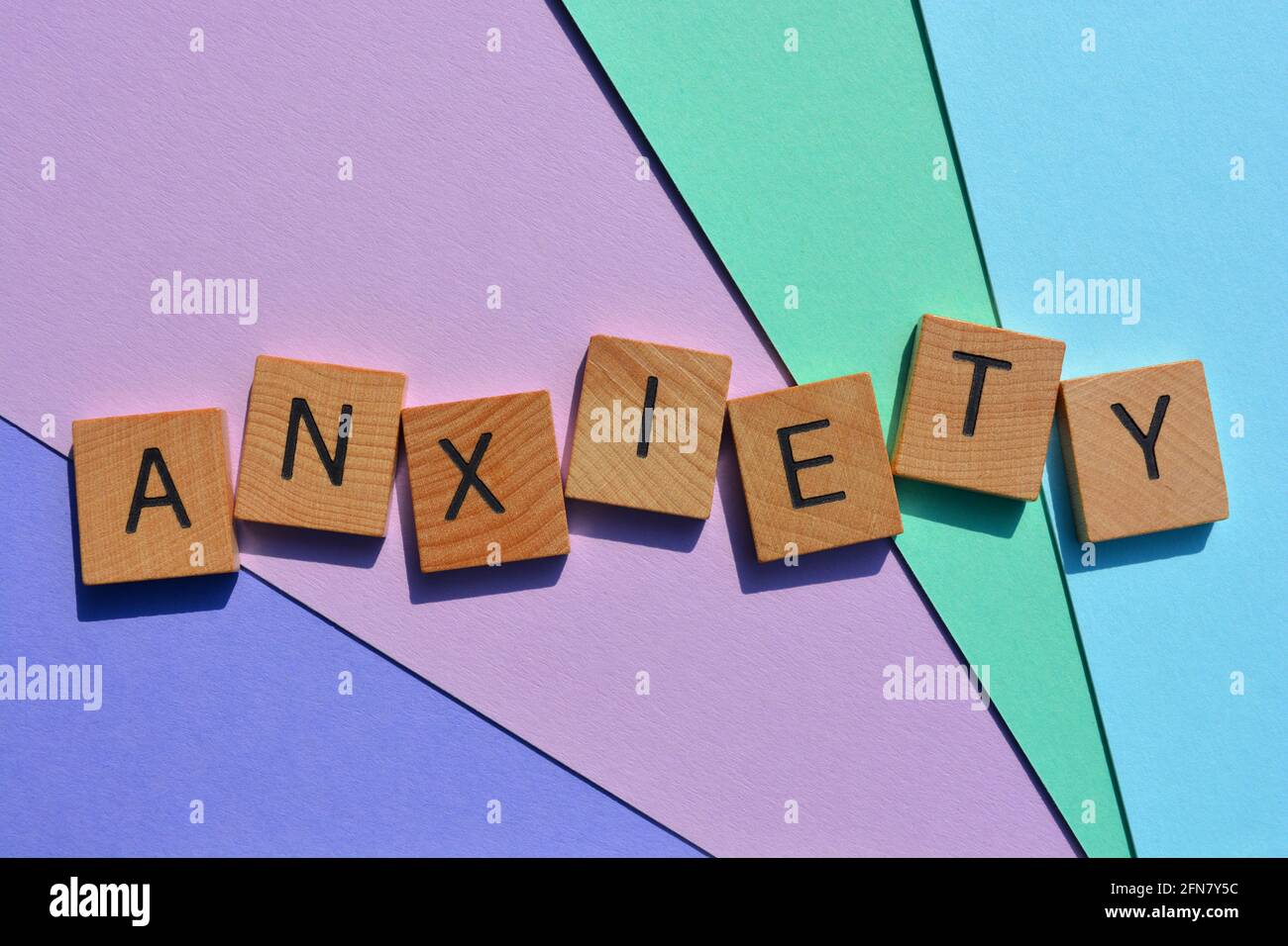 Anxiété, mot en lettres de l'alphabet de bois isolées sur fond pastel Banque D'Images