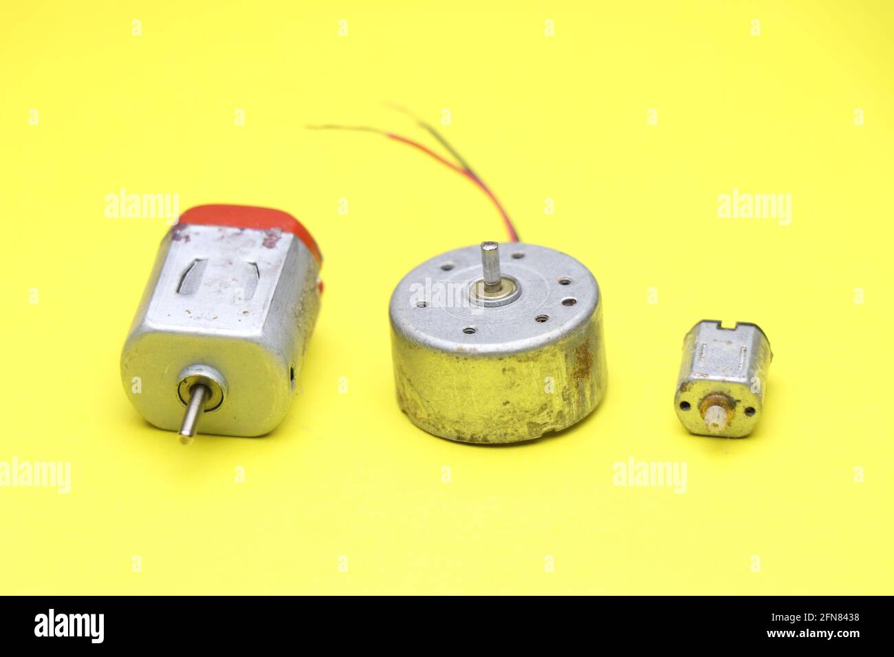 Moteur cc jouet avec moteur DVD et micro servomoteur sur fond jaune. Moteur c.c. à arbre simple utilisé dans divers projets électroniques Banque D'Images